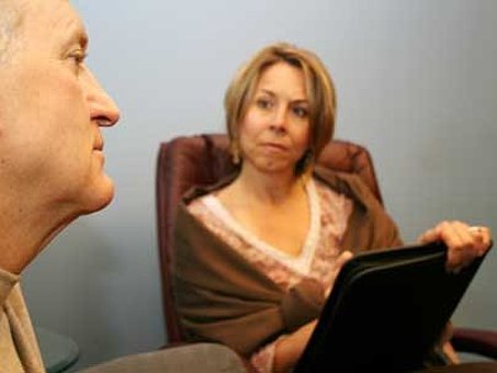 Beratungsgespräch: ein älterer Herr links blickt nachdenklich, während die Beraterin rechts im aufmerksam zuhört